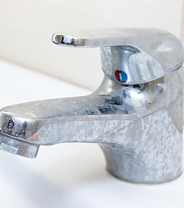Dirty faucet with limescale, calcified water tap with lime scale on washbowl in bathroom.