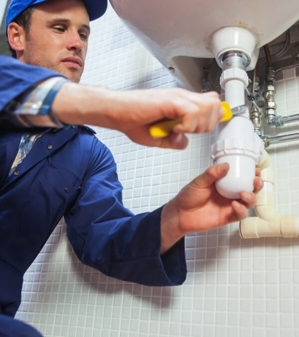 Frowning plumber repairing sink in public bathroom