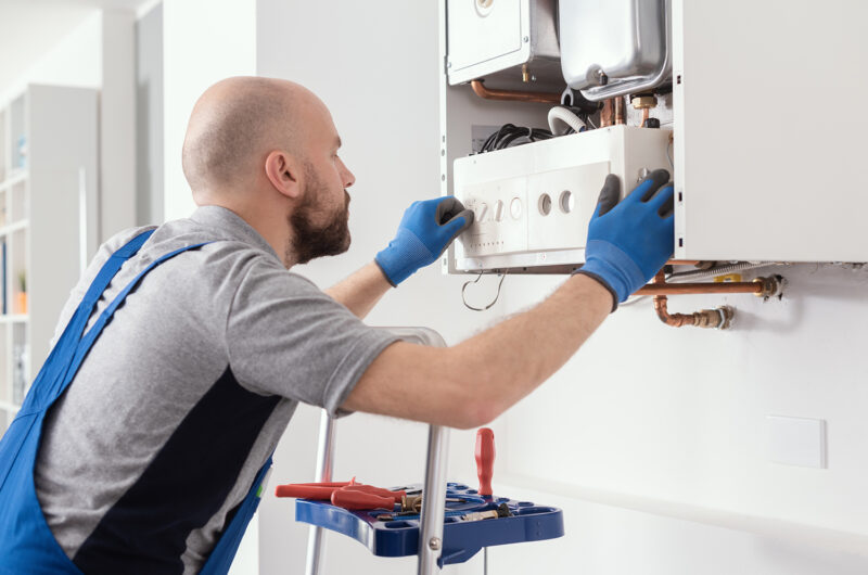 Professional engineer servicing a boiler at home Professional qualified engineer testing a gas boiler after repair